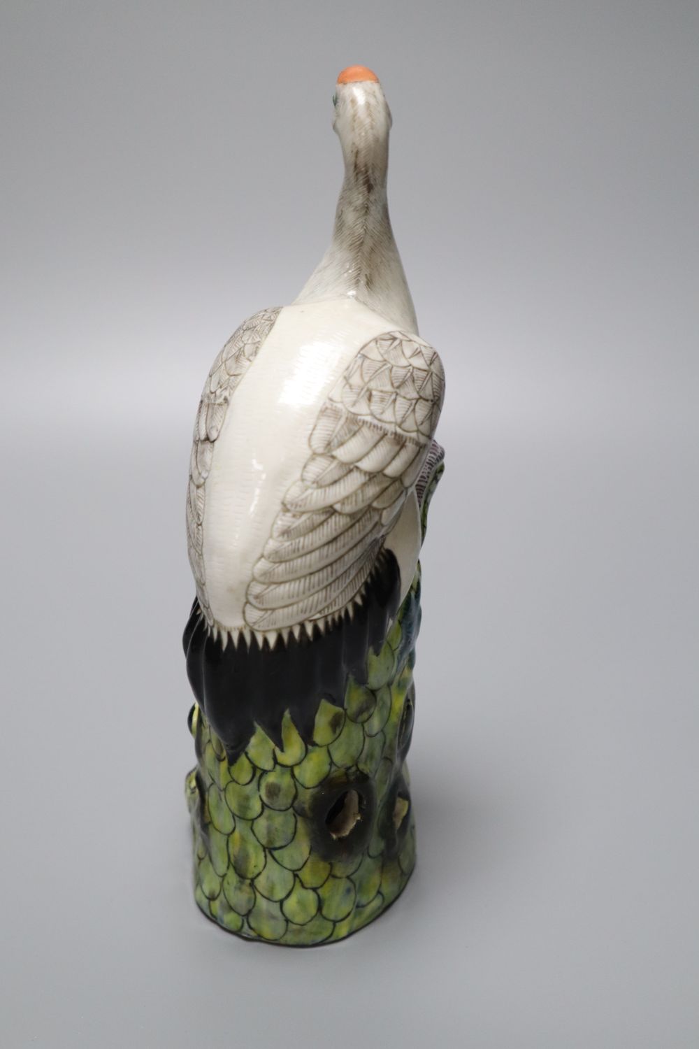 A Chinese enamelled porcelain model of a crane, 19th / 20th century, standing on a pine tree bough, height 24.5cm